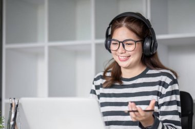 Oturma odasında dizüstü bilgisayarla internet üzerinden mutlu bir şekilde çalışan genç kız öğrenci...