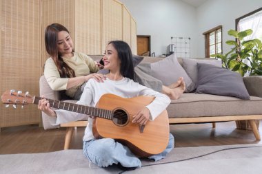 LGBT. İki genç kadın gitar çalıyor ve birlikte salonda şarkı söylüyorlar...