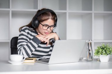 Oturma odasında dizüstü bilgisayarla internet üzerinden mutlu bir şekilde çalışan genç kız öğrenci...