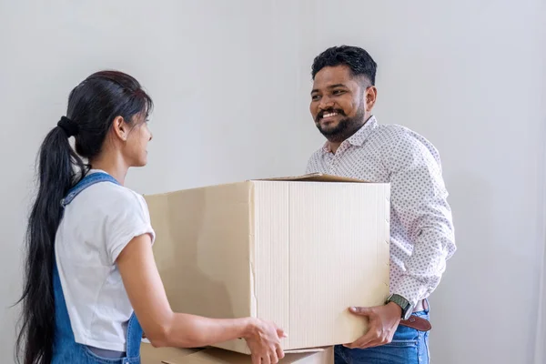 A couple moves into a new house. happily holding boxes and moving things together..