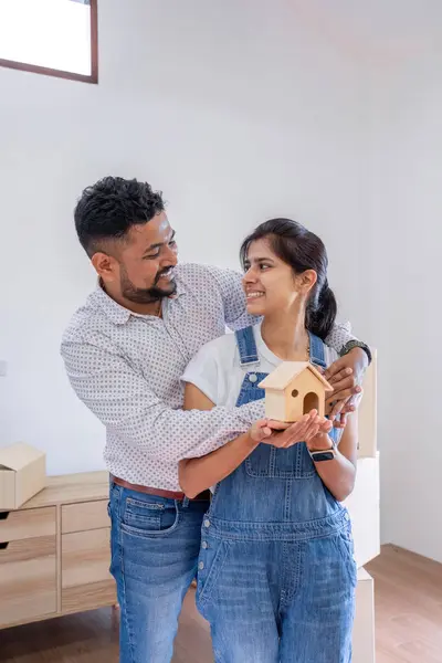 Happy couple holding house model on moving day to new house..