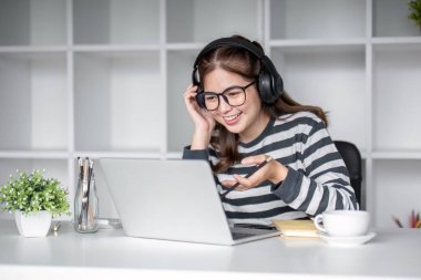 Oturma odasında dizüstü bilgisayarla internet üzerinden mutlu bir şekilde çalışan genç kız öğrenci...
