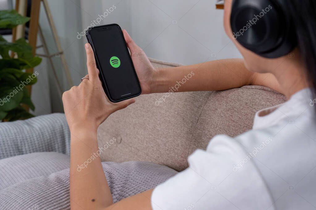 CHIANG MAI, THAILAND - AUG 28 2023: Person holding a brand new Apple iPhone 14 with Spotify logo on the screen. Spotify is a popular commercial music streaming service..