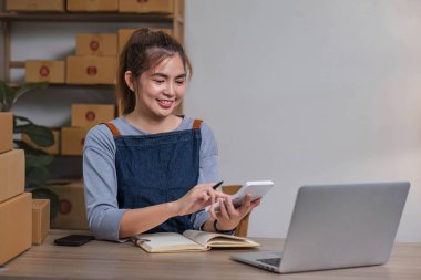 KOBİ girişimcileri, alınan emirlere göre ürünlerin değerini hesaplamak için hesap makinesine basıyorlar. Satın alma emrini kontrol et teslimat için paketleri hazırla..