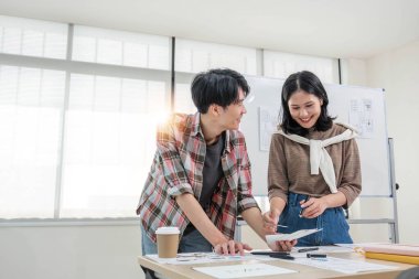 Zeki ve yakışıklı bir Asyalı genç erkek web sitesi geliştiricisi ofiste bir bayan meslektaşıyla yeni bir proje hakkında konuşuyor ve planlıyor. UI, UX, Tech Startup..