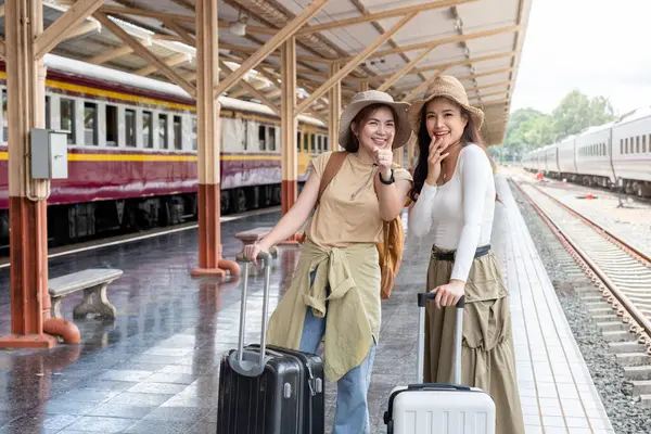 Two women are waiting for the train to travel together..