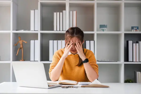 asian woman looks stressed due financial problem bills, calculator, laptop, holds head in hands, feels hopeless. Late loan payment, bankruptcy, lack of money to pay utilities concept.