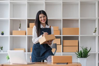 Portre işindeki kadın gülümse ve müşteriye gönderilmeden önce paket kutusundaki bilgileri kontrol et. Girişimci, evde çalışan küçük bir işletme. KME işi çevrimiçi pazarlama..