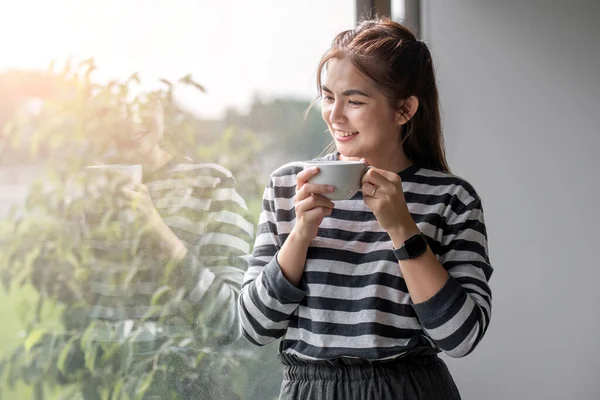 Portrait of beautiful young woman with a cup of coffee and wearing headphones standing relaxed and happy..