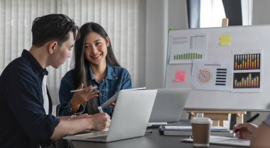Genç iş kadını, konferans odasında takım arkadaşlarına iş planını açıklıyor.