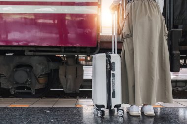 Elinde bavul tutan genç bir kadın. Tatilde trenle seyahat etmekten mutlu...