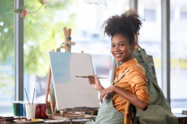 Stüdyosunda büyük bir zevkle çeşitli sanat projeleri üzerinde çalışan Afrikalı bir kadın ressamın portresi..