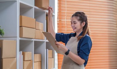 KOBİ girişimcileri paket kutusunun önüne bilgi yazıp sırayı ve sırayı kontrol ederler. Paketleri teslimat için hazırlayın...