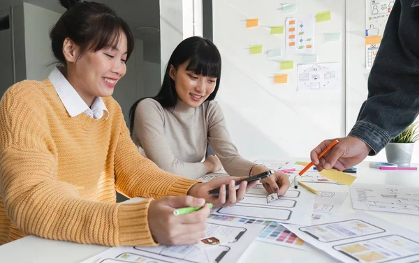 stock image Image of a team of developers brainstorming UI and UX design ideas for a mobile app on a paper wireframe interface. Planning the user interface development team for an intuitive UI design..