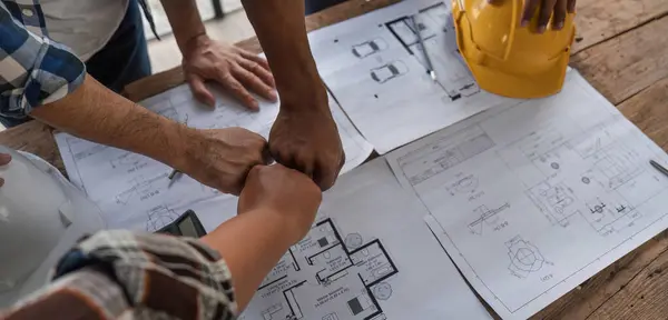 A team of engineers who successfully planned work on a modern home construction project shook hands and congratulated the team on their success..