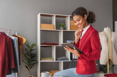 Moda tasarımcısı genç güzel kadının portresi. Renk örnekleriyle çalışıyor. Moda stüdyosunda renkli kumaşlarla çalışan genç Asyalı kız..