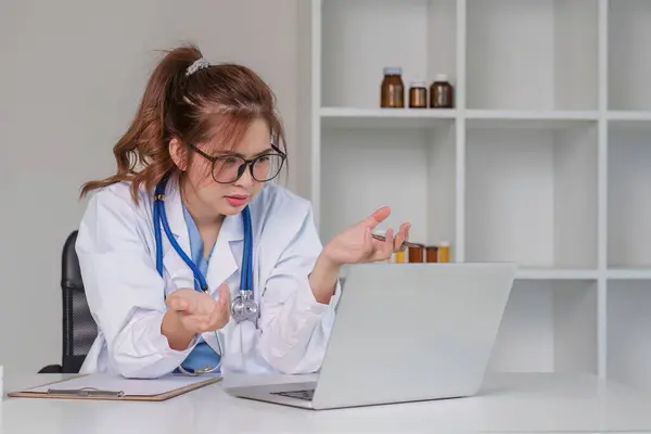 Stressed young female doctor looking at laptop, work related chaos, worried about mistake at work The stressed-out, unhappy medical professional is tired of solving computer problems at work..