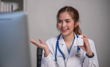 Genç, güzel doktor elinde ilaç şişesiyle klinikte laptopla tıbbın detaylarını anlatıyor..