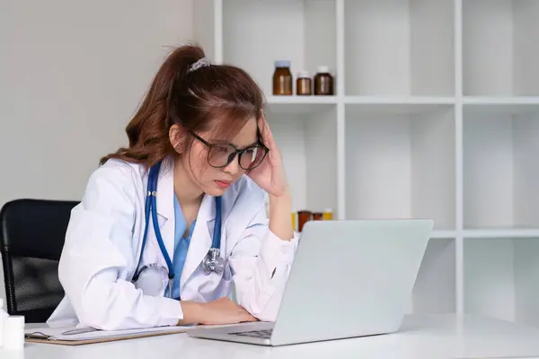 Stressed young female doctor looking at laptop, work related chaos, worried about mistake at work The stressed-out, unhappy medical professional is tired of solving computer problems at work..