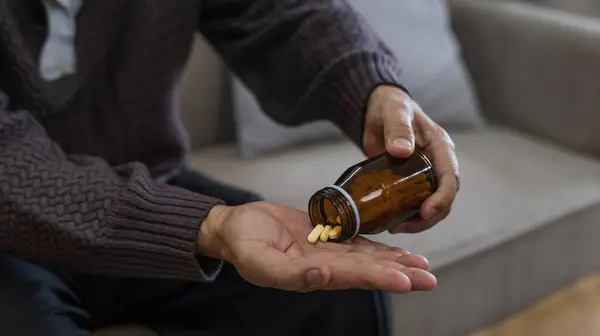 Close-up shot of medicine and hand of elderly person with pills in palm Caring for the health of the elderly with medicine to treat joint pain and arthritis in retirement.