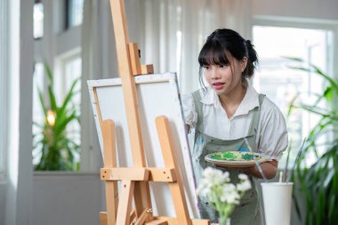 Genç kadın ressam, resim stüdyosunda soyut akrilik resim üzerinde çalışıyor...