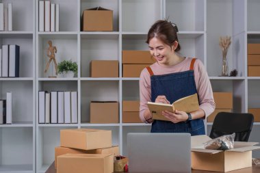 Girişimci elinde kalemle hesap makinesi kullanıyor, ev ofisinin mali giderlerini hesaplıyor, çevrimiçi pazar paketleme kutusu teslimatı, başlangıçta başarılı küçük işletme sahibi KME, konsept.