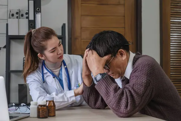 A female doctor is giving advice on diseases and medicine to an elderly male patient. 60s who has a headache Concept of health check and stress disease.