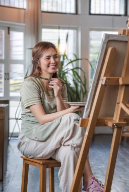 Genç kadın ressam, resim stüdyosunda soyut akrilik resim üzerinde çalışıyor...