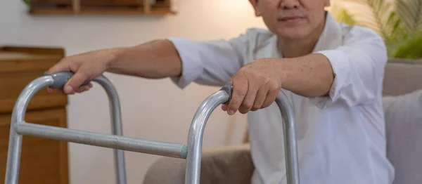 stock image Asian woman caregiver helping senior man walking. Nurse assisting he old man patient at nursing home. Senior man using walker being helped by nurse at home. Elderly patient care and health lifestyle.