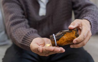 Avuçlarında haplarla yaşlıların eklem ağrısını tedavi etmek için ilaç ve el hapları ile yaşlıların sağlığını gözetiyor.