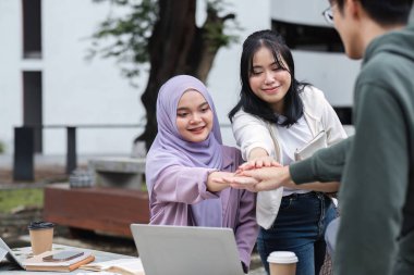 Takım çalışması planlama konusunda fikir alışverişinde bulunan çekici bir grup öğrenci üniversite tezgahında sınavlara hazırlanmak için birbirlerine yardımcı oluyorlar...