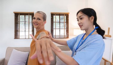 A caregiver is helping an elderly person with physical therapy in the living room of a home. Happy elderly man doing physical therapy in his home with a caregiver nearby.. clipart