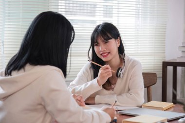 Mutlu genç bir Asyalı adam ve güzel bir kız birlikte dizüstü bilgisayarda çalışıyorlar, ortak bir proje üzerinde çalışıyorlar, fikirleri paylaşıyorlar ve bir odada iş tartışıyorlar...