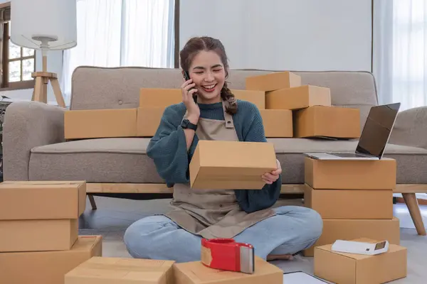 Small start-up business owners using phones at work, salespeople, checking production orders. Pack products to ship to customers, sell ecommerce shipping ideas..