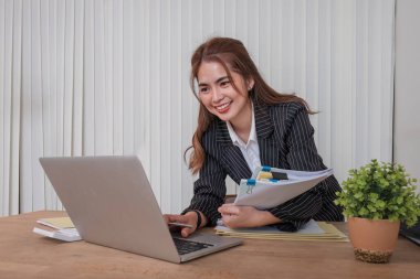 Ofiste dizüstü bilgisayarda çalışan neşeli iş kadını, iş yerinde resmi takım elbiseli Asyalı mutlu iş kadını. Çekici bayan ofis çalışanı gülümsemesi..