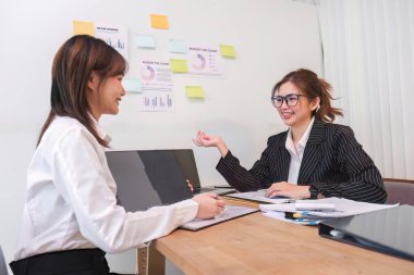 Ofis konferans odasında proje stratejisini tartışan iki işadamı iş arkadaşlarıyla proje planlamasını tartışıyor ve mali rapor hakkında tavsiyelerde bulunuyor..