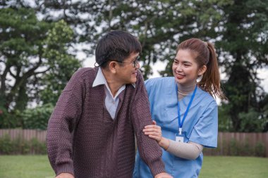 Asyalı kadın bakıcı, yaşlı bir adamın yürüteçle yürümesine yardım ediyor. Evde bir hemşire de ona yardım ediyor. Hemşire, huzurevindeki yaşlı bir hastaya yardım eder. Yaşlı bakımı ve sağlıklı yaşam tarzı.