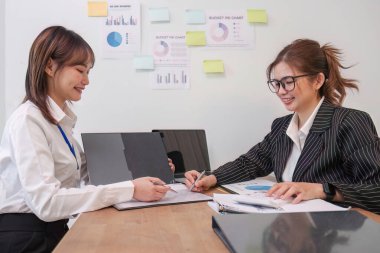 İş adamları toplantı odasında proje stratejisi hakkında konuşuyorlar. İş adamı, mali veri raporu hakkında sohbet ve tavsiyelerde bulunurken, modern işyerindeki iş arkadaşıyla proje planlamasını tartıştı..