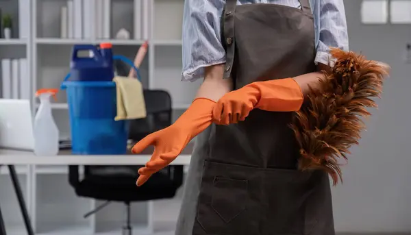 close up, A young cleaning lady is wearing glove and preparing to clean the office. Young housewife with Chicken feather duster and cleaning equipment in the office Cleaning concept.