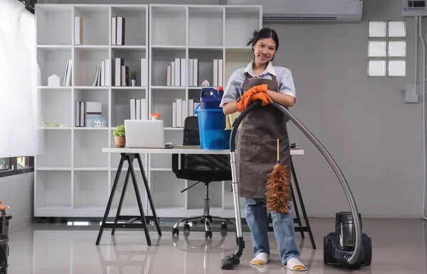 Cleaning in the office Beautiful cleaning lady uses a mop and a vacuum cleaner to clean the floor and get rid of dust. Cleaning concept Housekeeping.