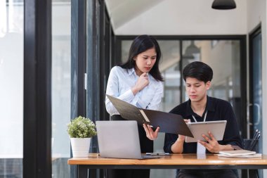 Ofis konferans odasında proje stratejisini tartışan iki işadamı, iş arkadaşlarıyla modern işyerindeki proje planlamasını tartışıyor ve mali raporlar hakkında görüş alışverişinde bulunuyor..