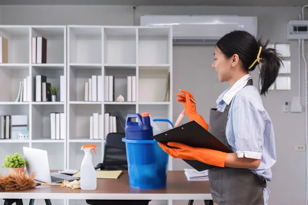 Young woman standing and checking cleaning item or cleaning supplies in office Cleaning staff or maid cleaning the office.