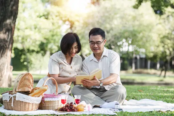 Senior couple picnicking in the park showing their love, support or reconnecting after retirement in a relaxed park. And elderly men and women happily sit on mats in the backyard to rest..