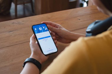 CHIANG MAI, THAILAND - 16 NOV 2023: Yeni giriş ekranı ile Facebook kullanmak için iPhone 14 'ü elinde tutan kadın. Facebook dünyadaki en büyük sosyal ağ ve en popüler sosyal ağ sitesidir...