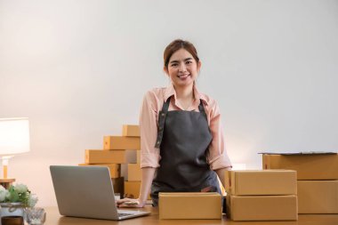 Küçük bir işletme kurma portresi KOBİ işletme sahibi kadın girişimci ticari kutular üzerinde çalışıyor ve müşterilere kutu hazırlamak için çevrimiçi siparişleri kontrol ediyor..