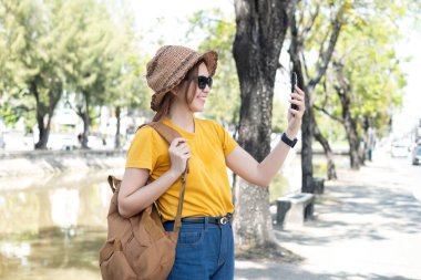 Genç Asyalı turist şehir sokaklarında yürüyor ve ödemede cep telefonu tutuyor..