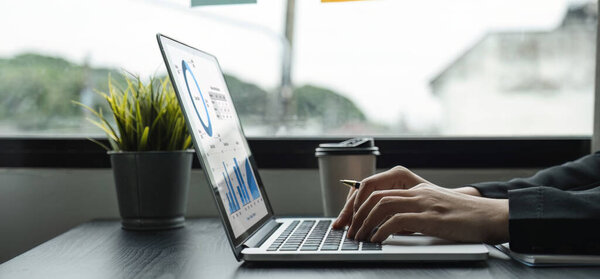 Молодая предпринимательница работает над графиками и графиками, показывающими организационные результаты..