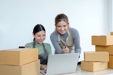 İki Asyalı girişimci kadın sipariş alır ve teslimat için müşteri siparişlerine göre kutuları işaretler...