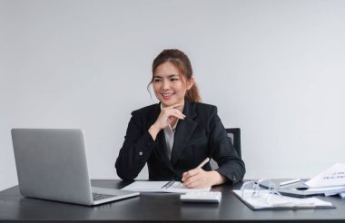 Şirket çizelgelerinde dizüstü bilgisayar ve ofis odasındaki ahşap masada grafikler kullanan çekici genç bir iş kadını..