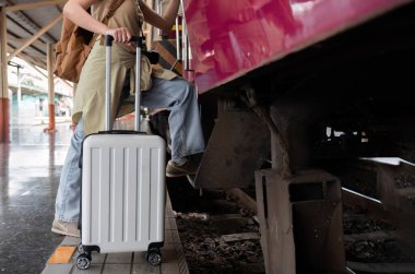 Elinde bavul tutan genç bir kadın tren istasyonunda tren beklerken hafta sonu seyahatinde, konsepti kapat...